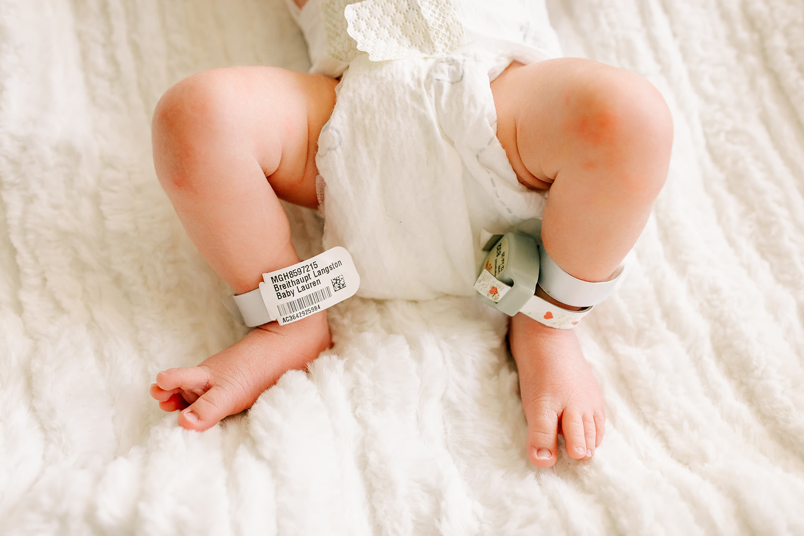 Details of a newborn baby's legs and feet with the hospital bands still on in a bed while using a diaper service in Boston