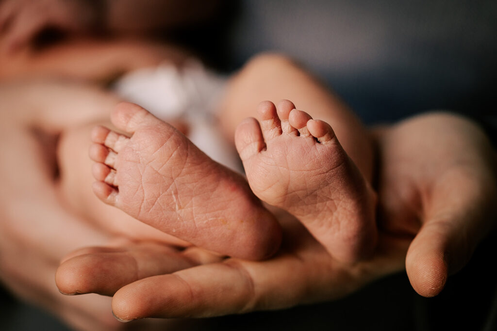 Details of a newborn's feet in a parent's hand thanks to a Midwife in Boston