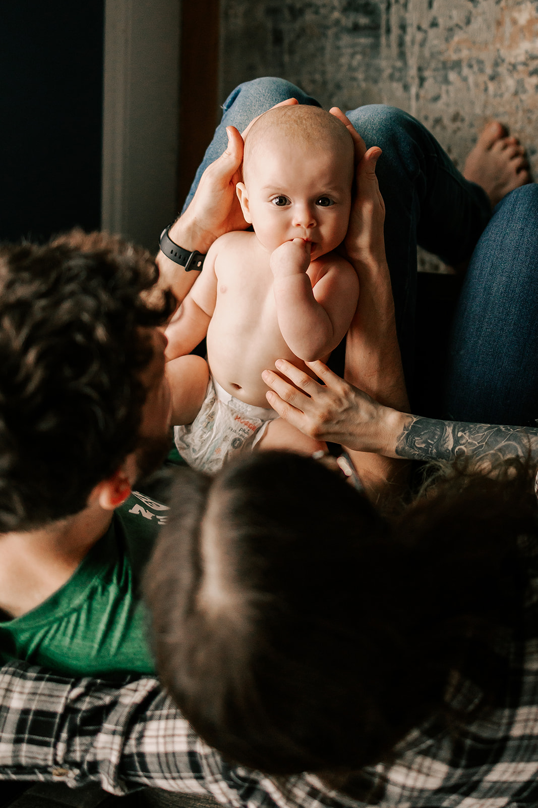 A newborn baby lays in dad's lap while looking up in a diaper thanks to an OBGYN in Boston