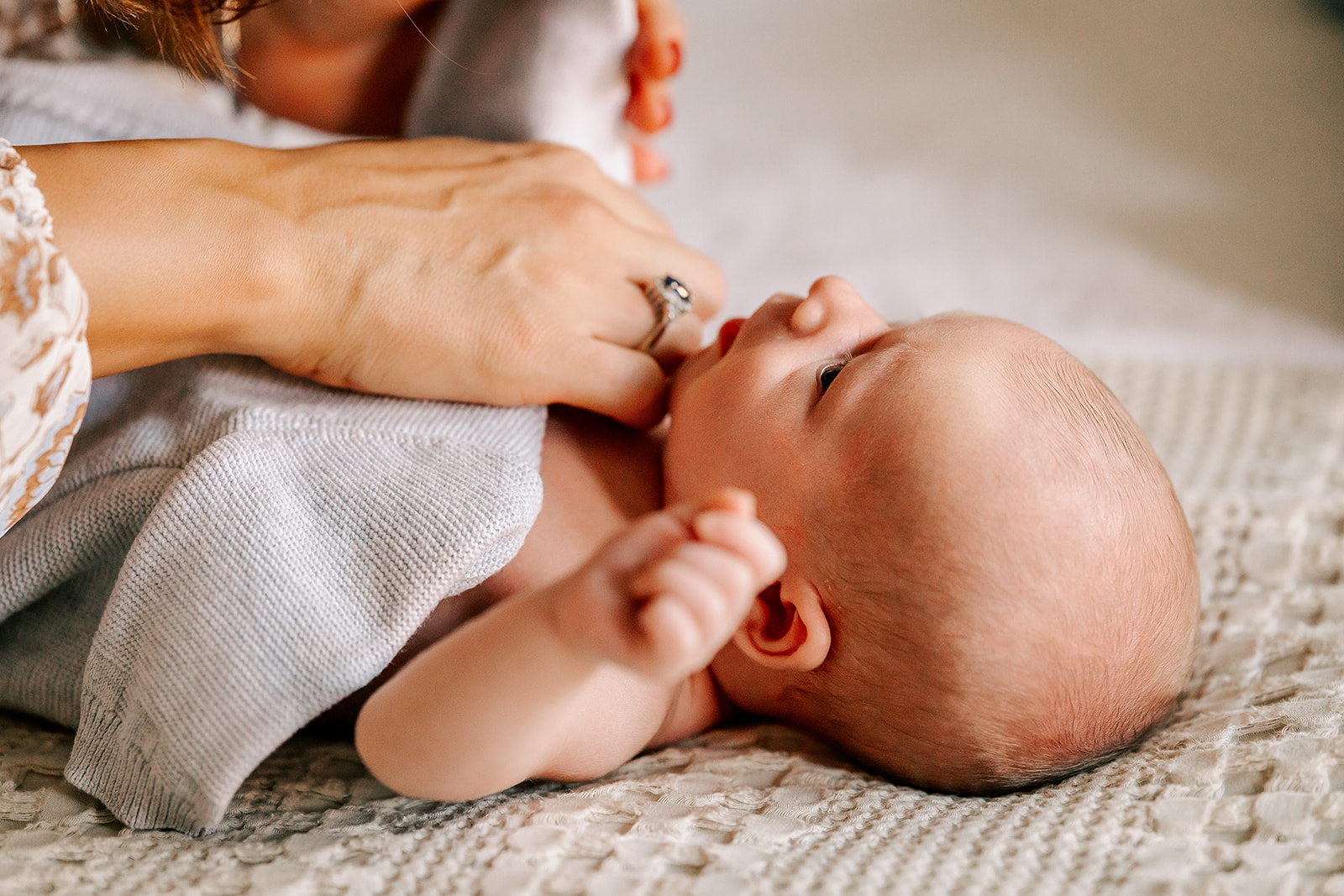 A newborn lays on a bed with mom snuggling after some placenta encapsulation in Boston