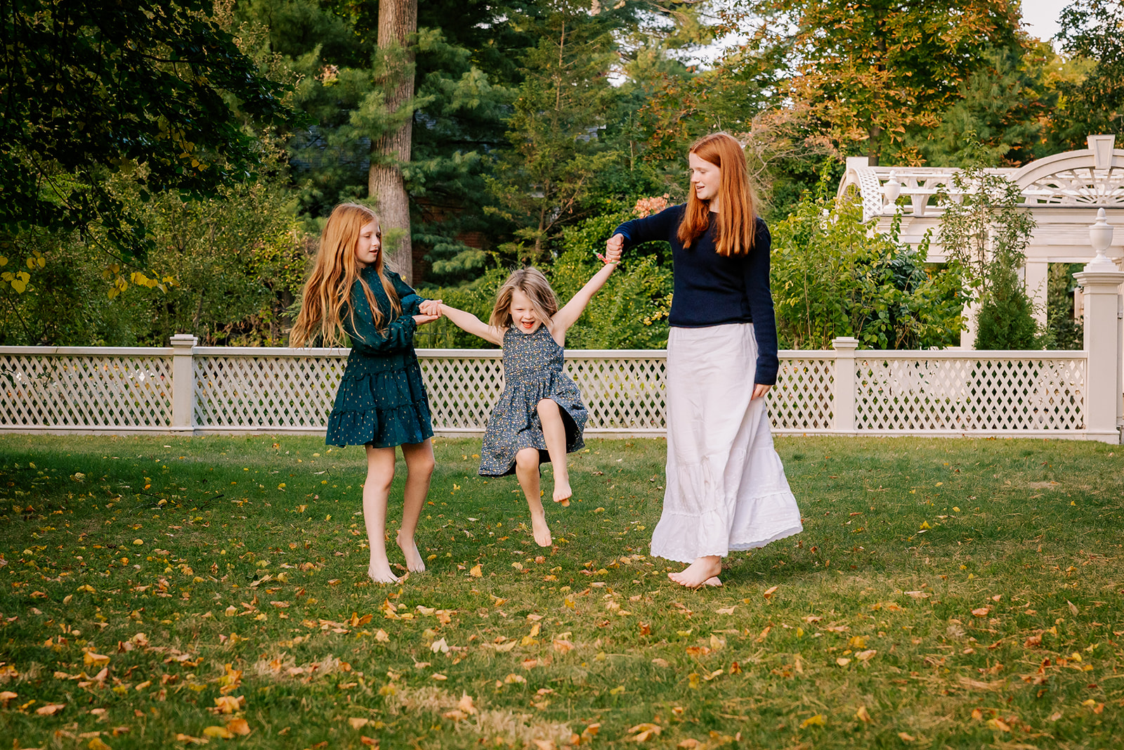 Three young sisters play and dance in a garden holding hands while staying at kid-friendly hotels in Boston