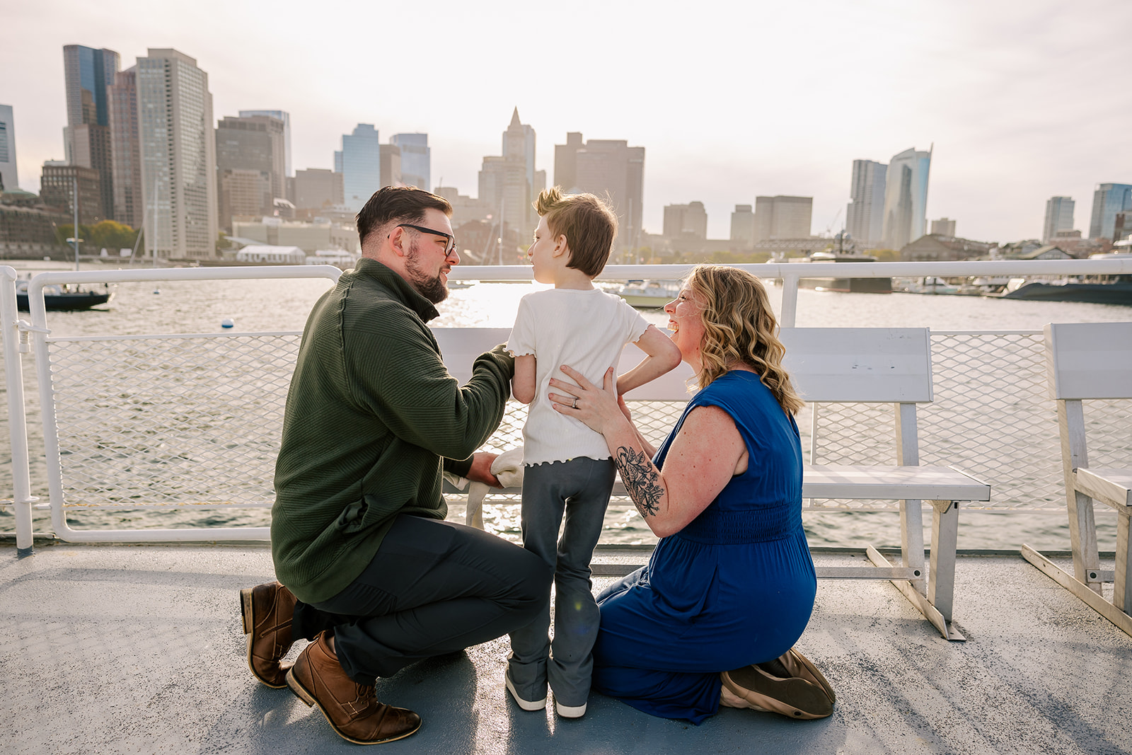 Happy parents laugh with their child by the water while admiring the skyline