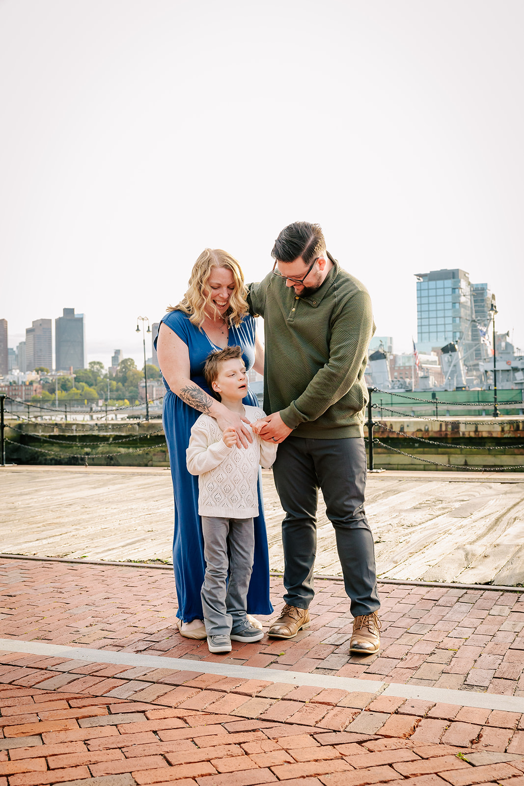 A happy family hugs by the water at the wharf at sunset after some kids birthday parties in Boston