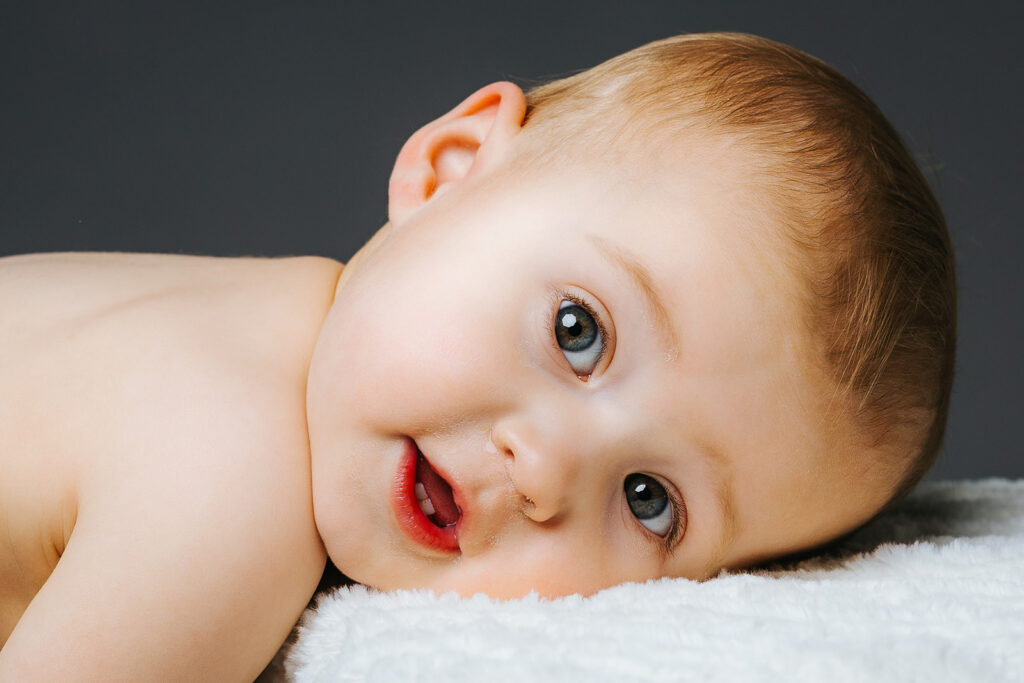A baby lays on a white blanket after finding a pediatric dentist in Cambridge, MA