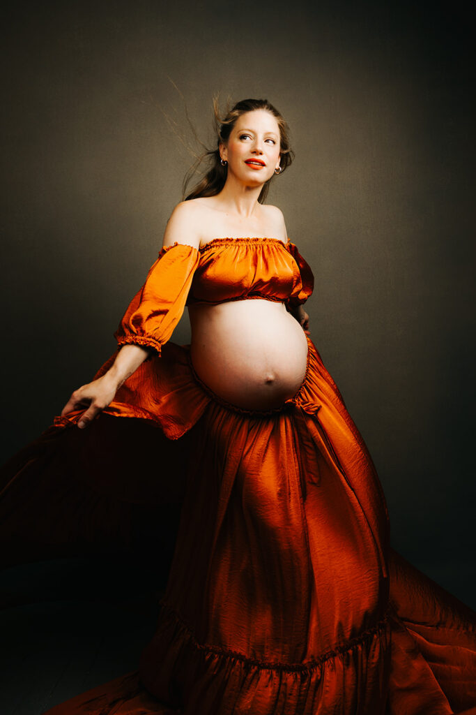 A mother to be dances in a studio wearing a two piece orange maternity outfit after some pelvic floor therapy in Cambridge, MA