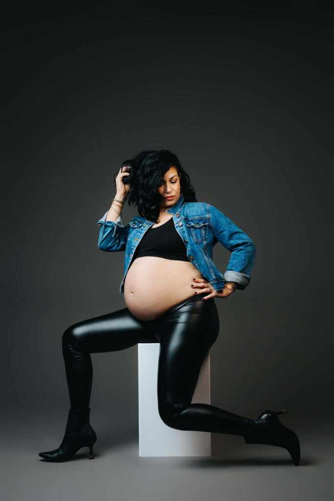 Mother-to-be in a high fashion pose against a grey studio backdrop. 